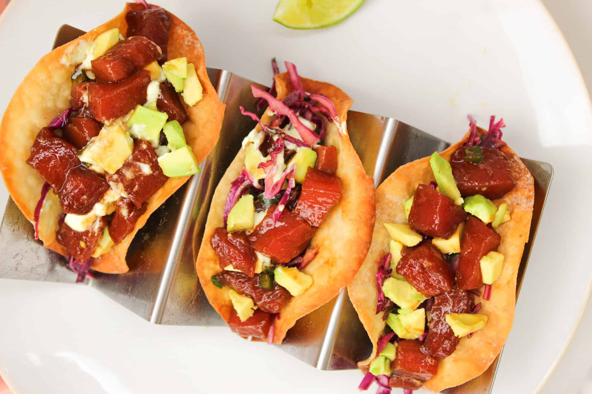 Overhead image of wonton taco shells stuffed with tuna, slaw, avocado, and wasabi cream.