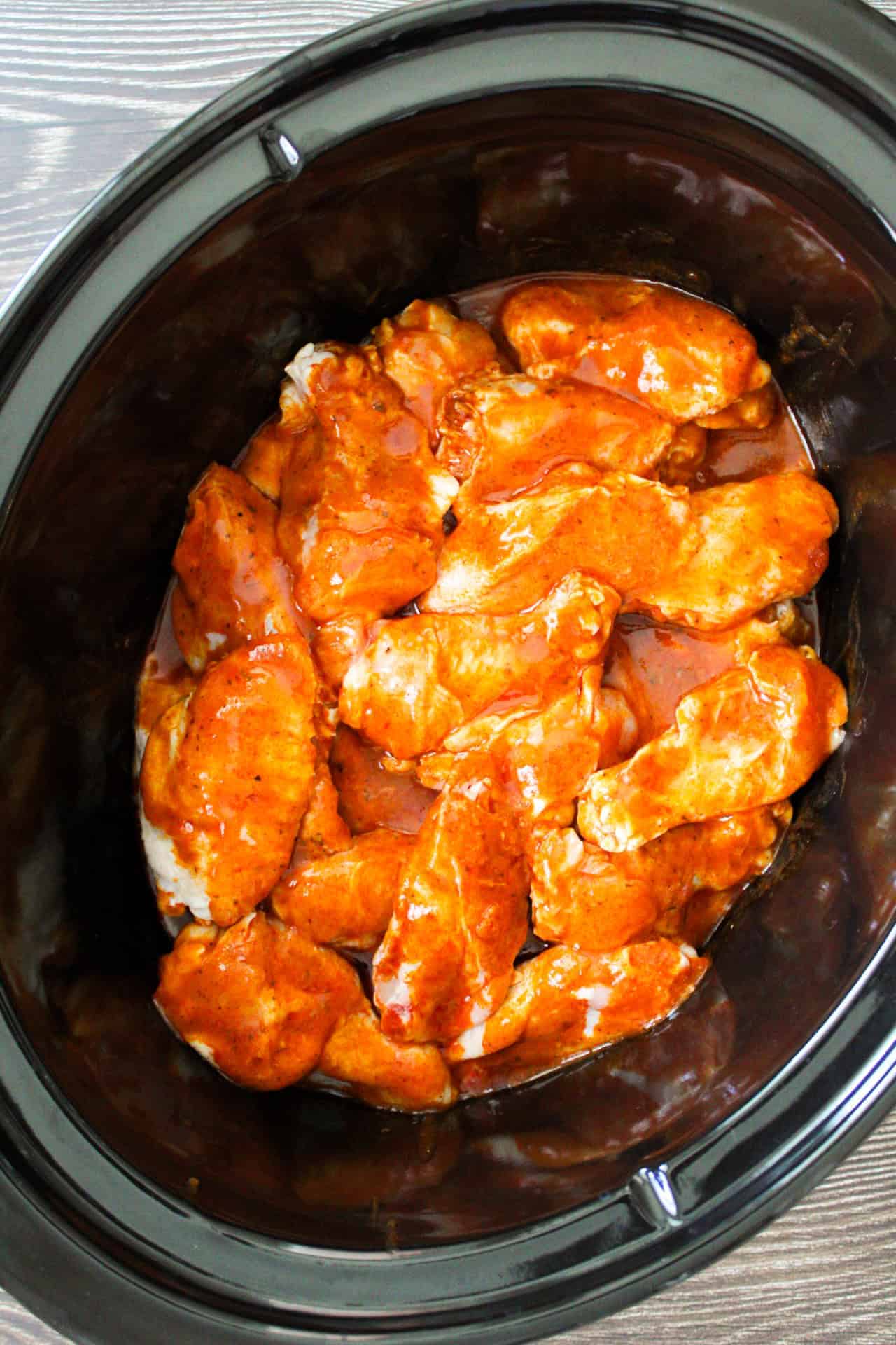 Chicken Wings in a crockpot tossed with buffalo sauce.