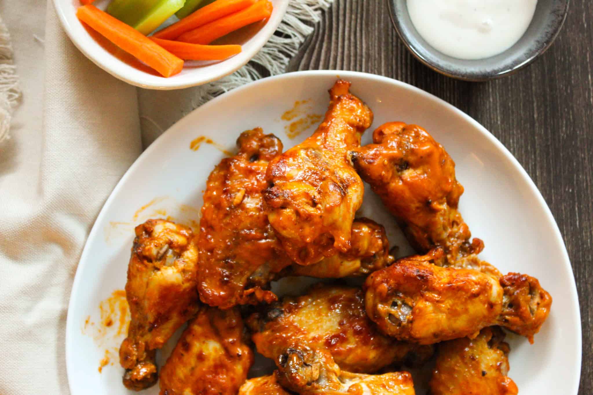 Chicken wings tossed in hot buffalo sauce on a plate.