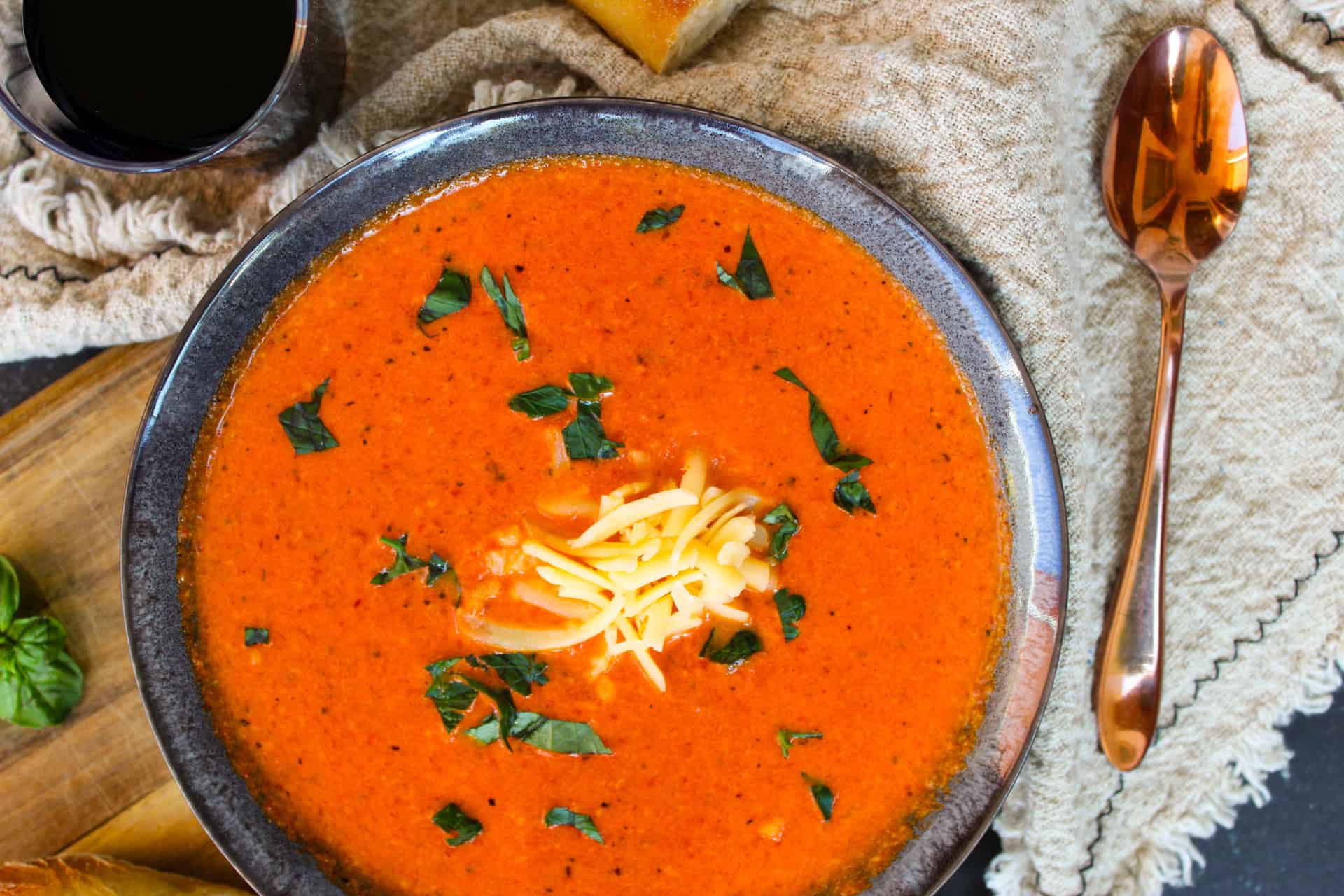 Overhead image of Roasted Red Pepper Soup topped with cheese and basil.