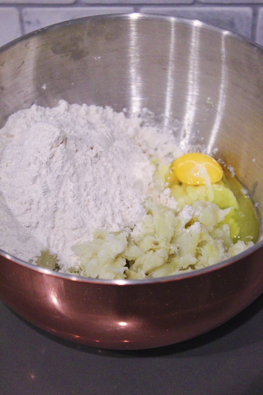 Flour, eggs, and potato in a large mixing bowl for gnocchi.