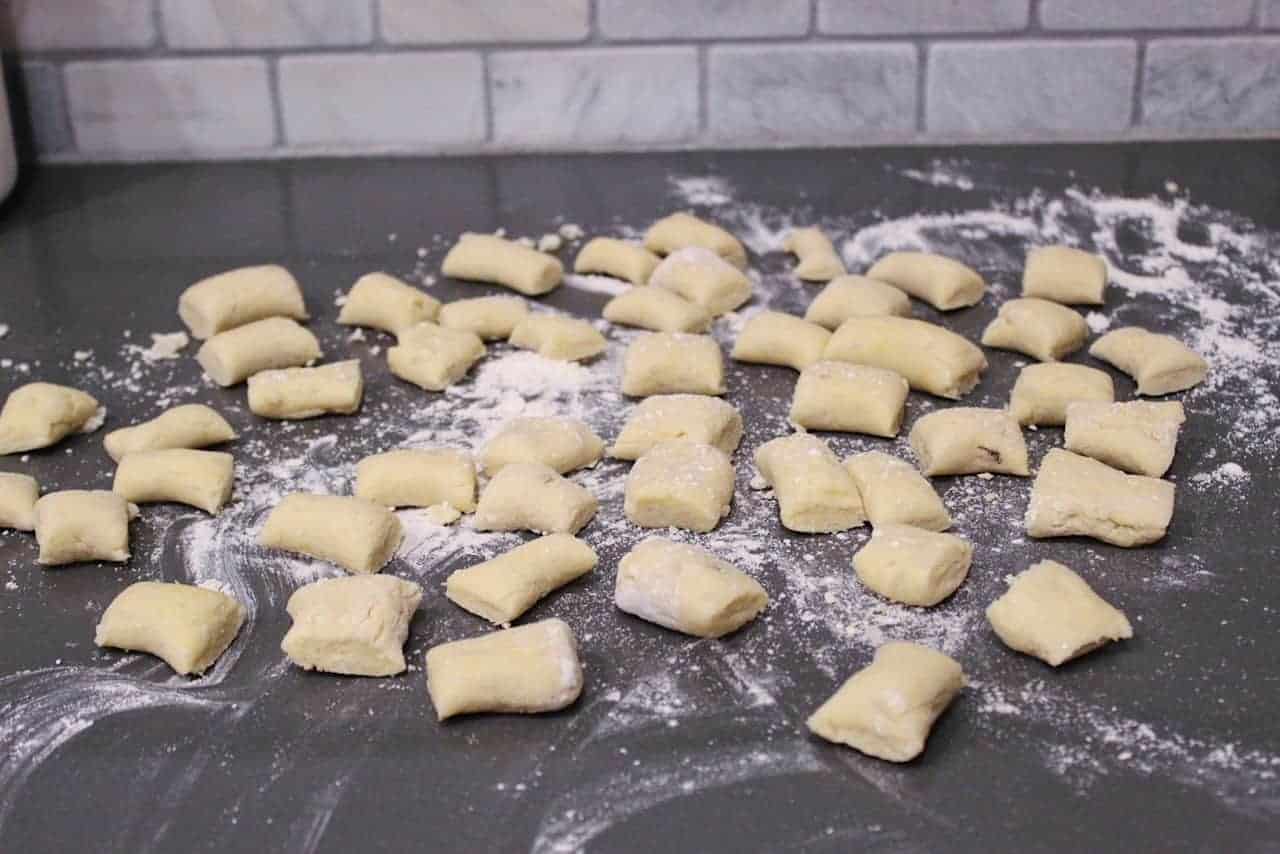 Homemade gnocchi and flour on grey countertop.