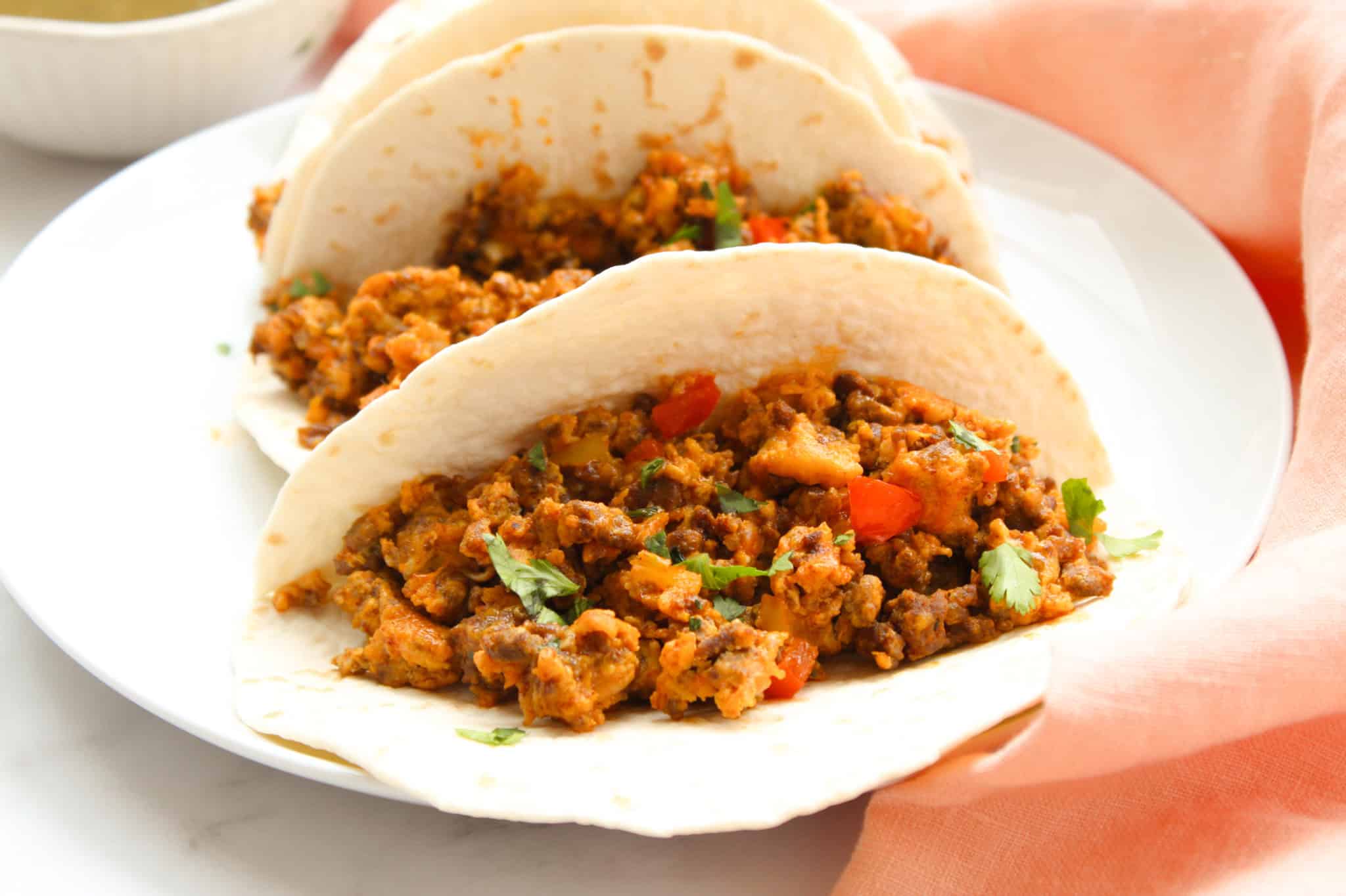 Close up image of a tortilla stuffed with chorizo, eggs, vegetables, and avocado. 