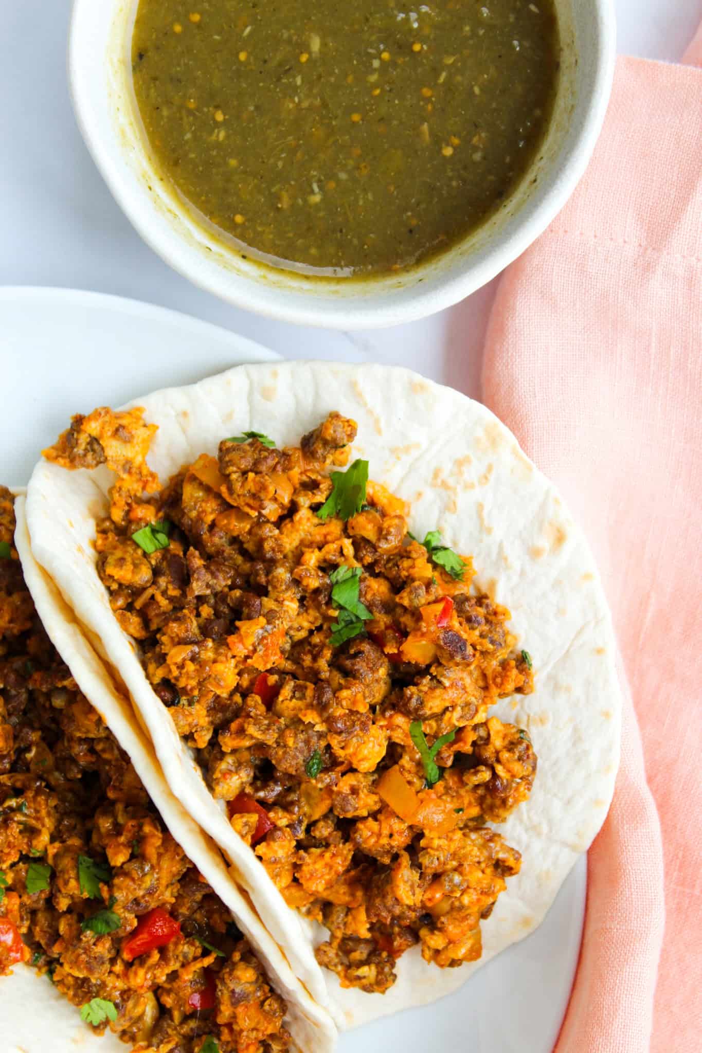 Chorizo and Egg Tacos with fresh cilantro next to a bowl of salsa. 