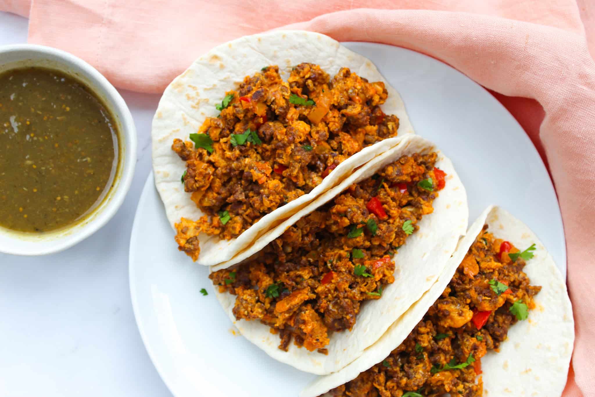 Three side by side chorizo tacos on a plate.