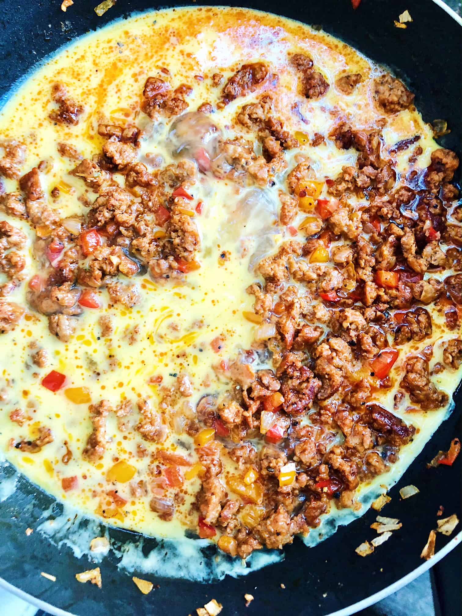 Eggs being scrambled in a skillet with chorizo.