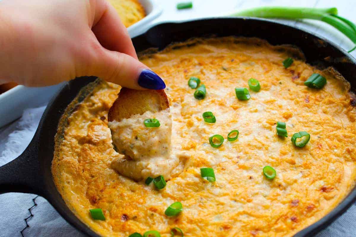 Dipping crostini into hot Cajun Crab Dip with green onions.