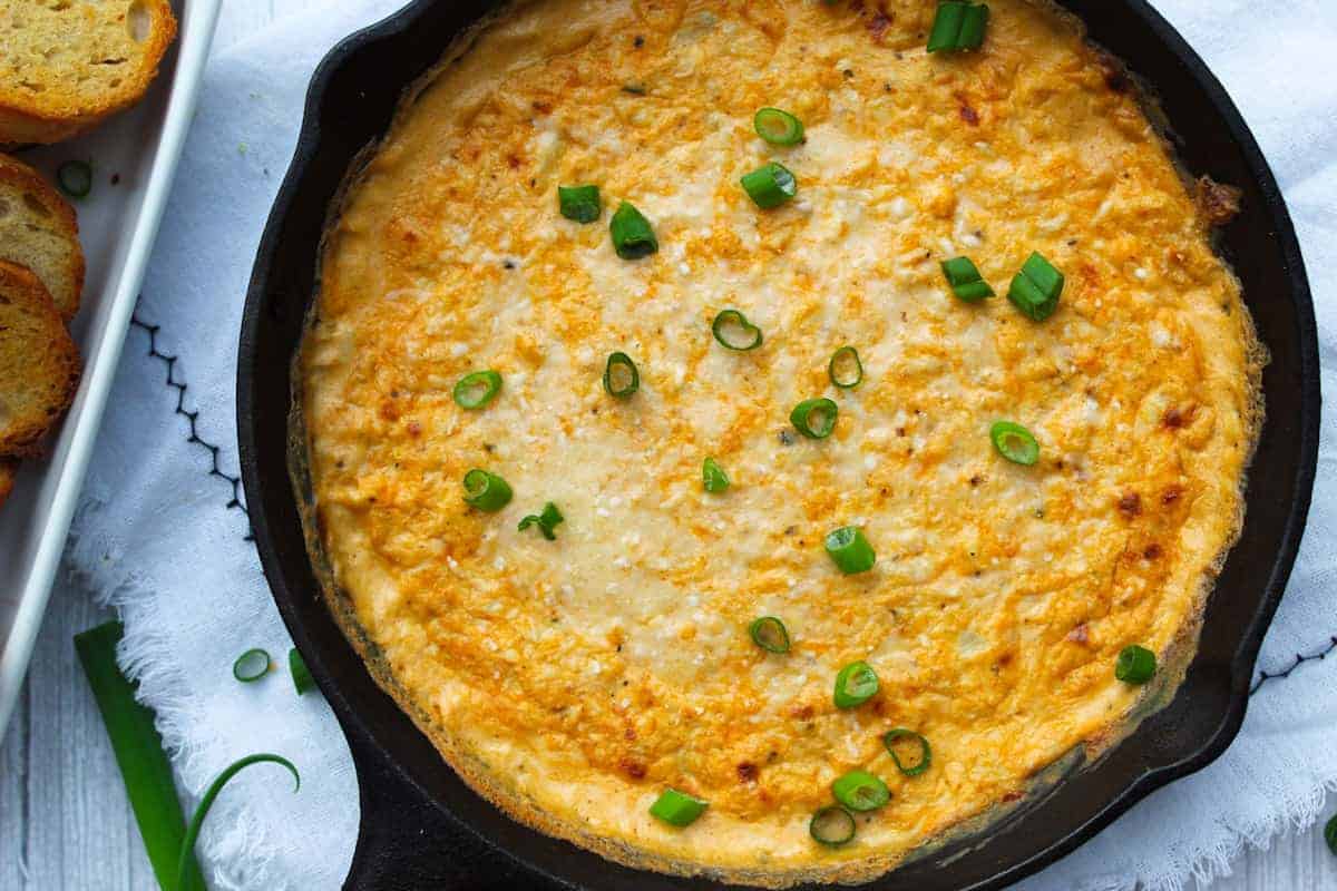 Close up of hot cajun crab dip with green onions on top.