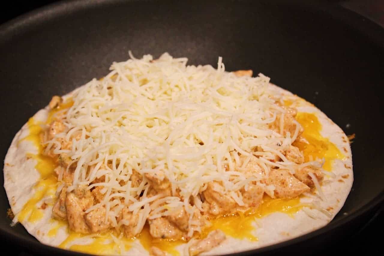 Tortilla topped with cheddar cheese, chicken, quesadilla sauce, and monterey jack cheese.