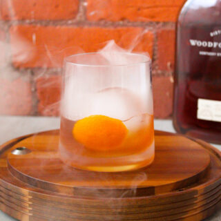 Old Fashioned sitting on wood base with smoked in the top.