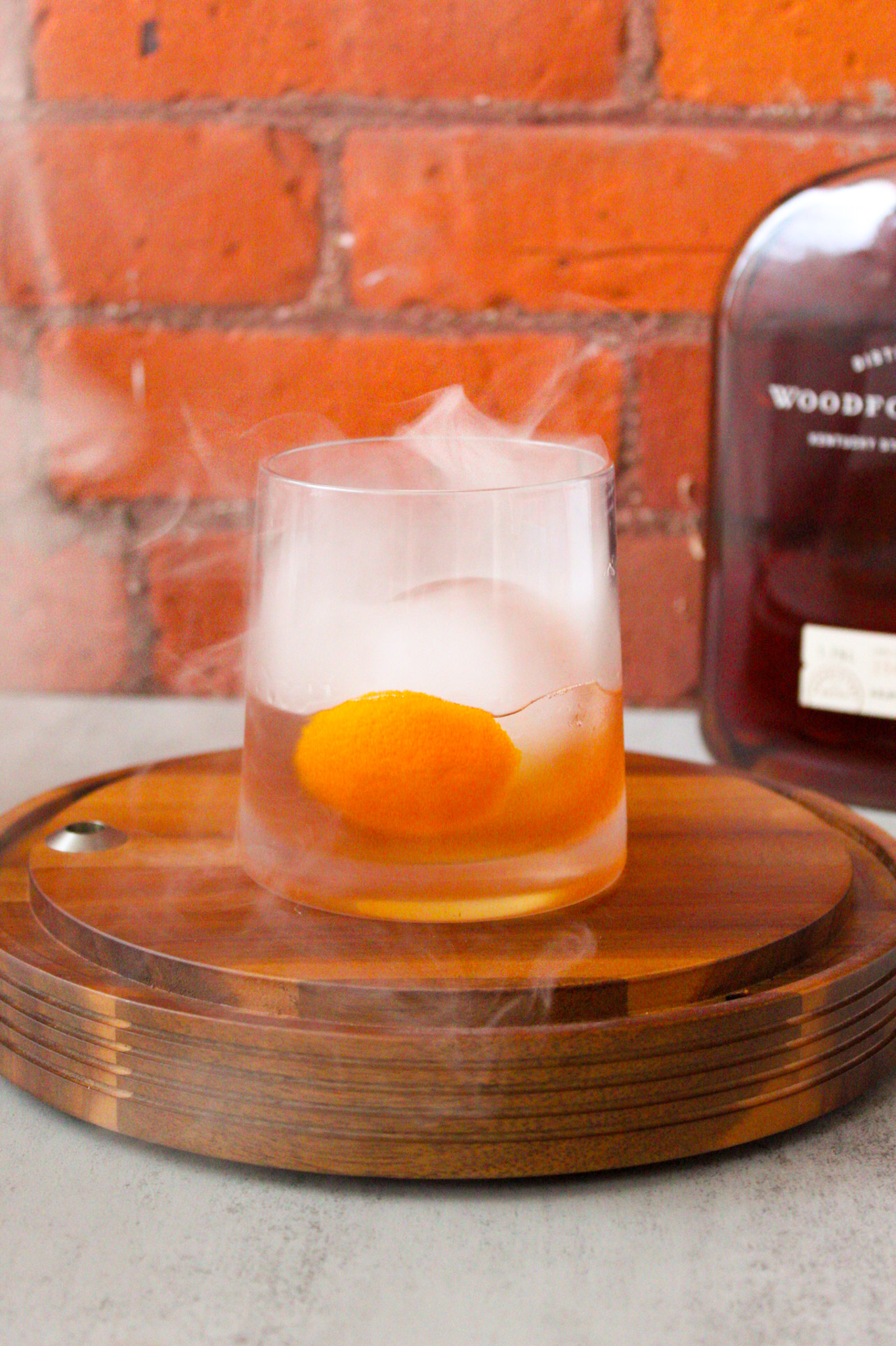 Old Fashioned sitting on wood base with smoked in the top.