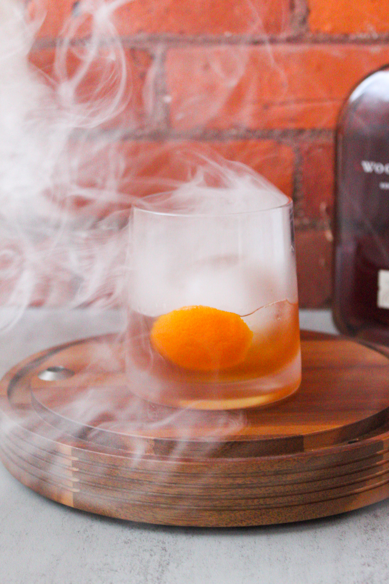 Cocktail in rocks glass surrounded by smoke.
