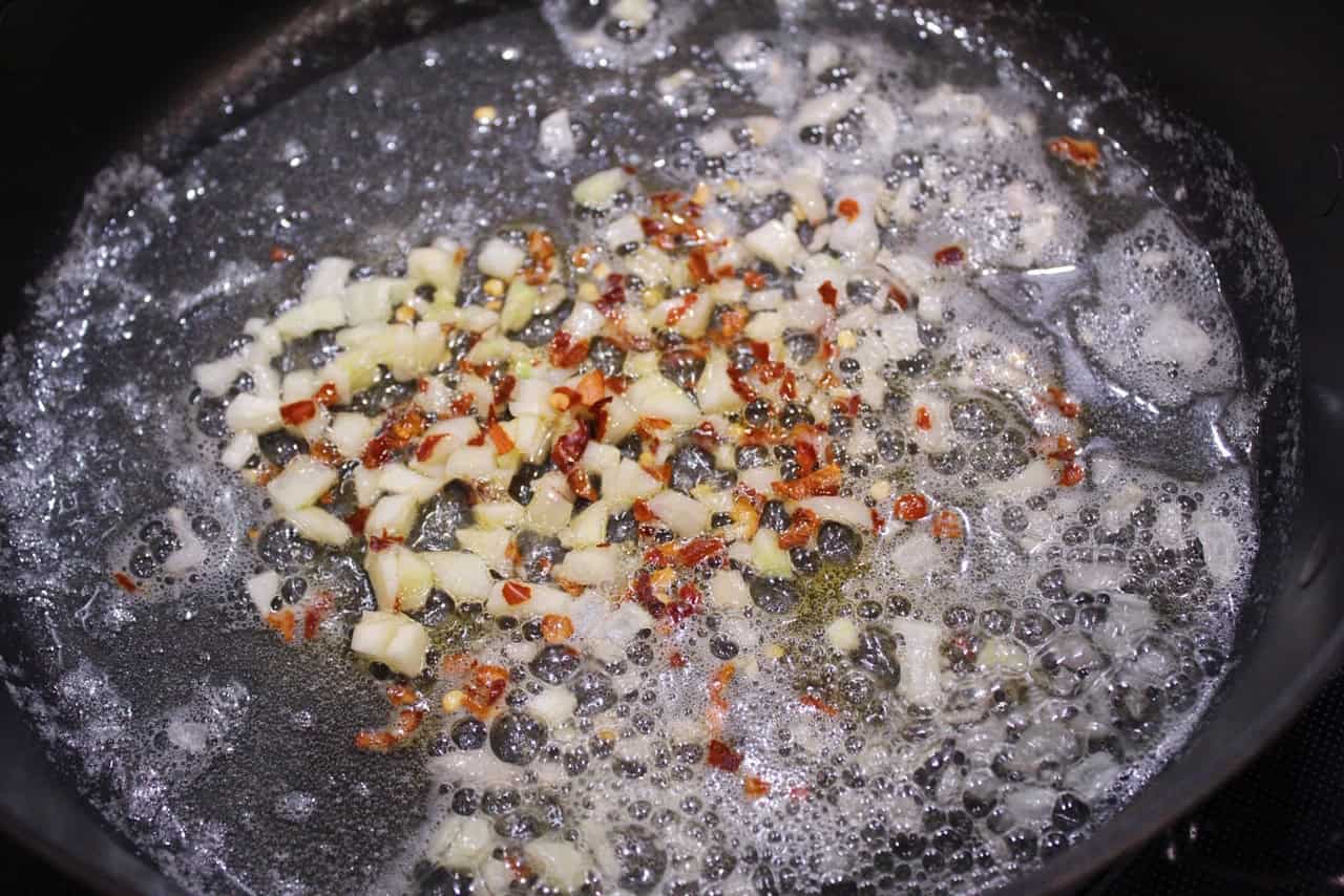 Sauteing garlic, shallot, and red pepper flakes in butter.