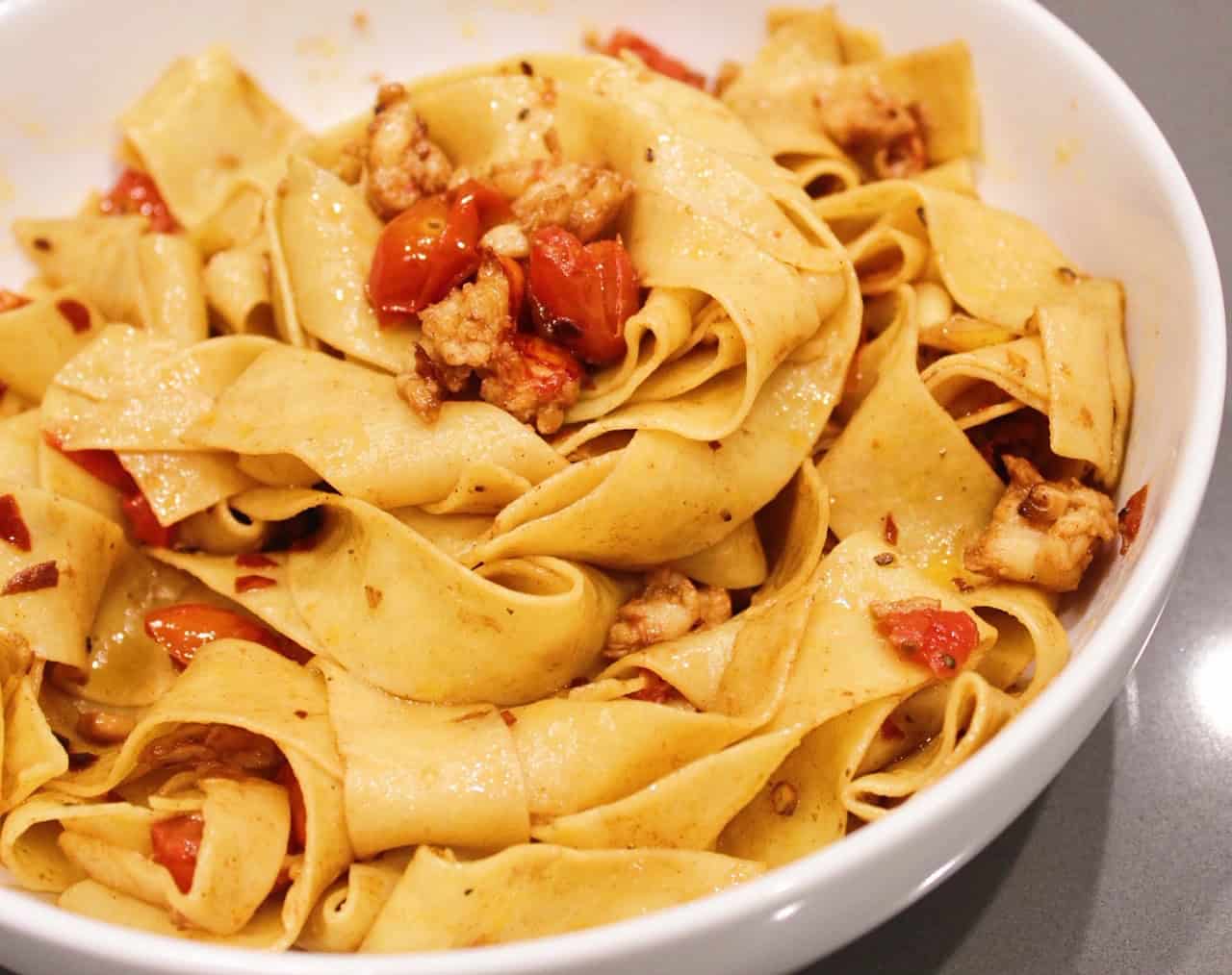 Lobster Pappardelle with tomatoes in a white bowl.