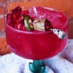 Close shot of vibrant pink prickly pear margarita garnished with slice of jalapeno.