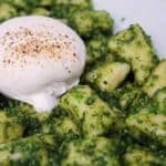 Homemade gnocchi covered in basil pesto and topped with burrata cheese.