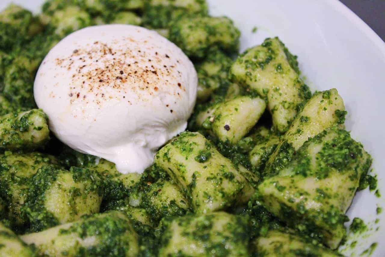 Homemade gnocchi covered in basil pesto and topped with burrata cheese.