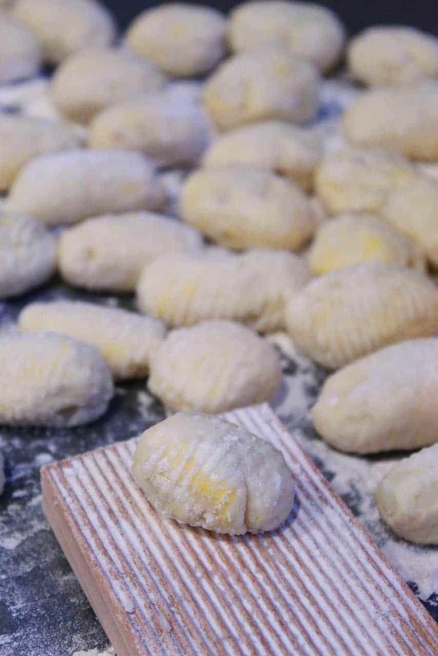 Homemade gnocchi being rolled on gnocchi board.