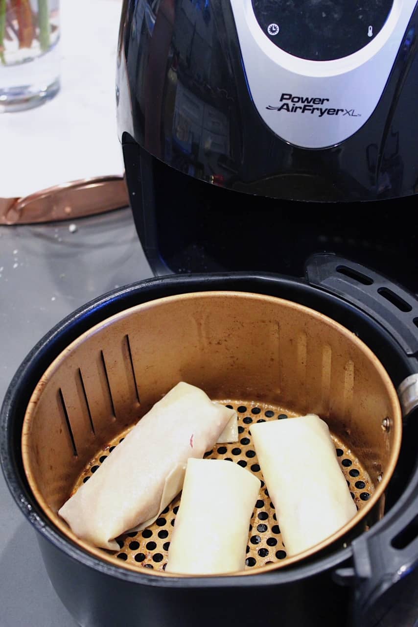 Reuben Egg Rolls in air fryer basket.