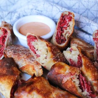 Reuben egg rolls close up on white serving plate with grey dish towel.