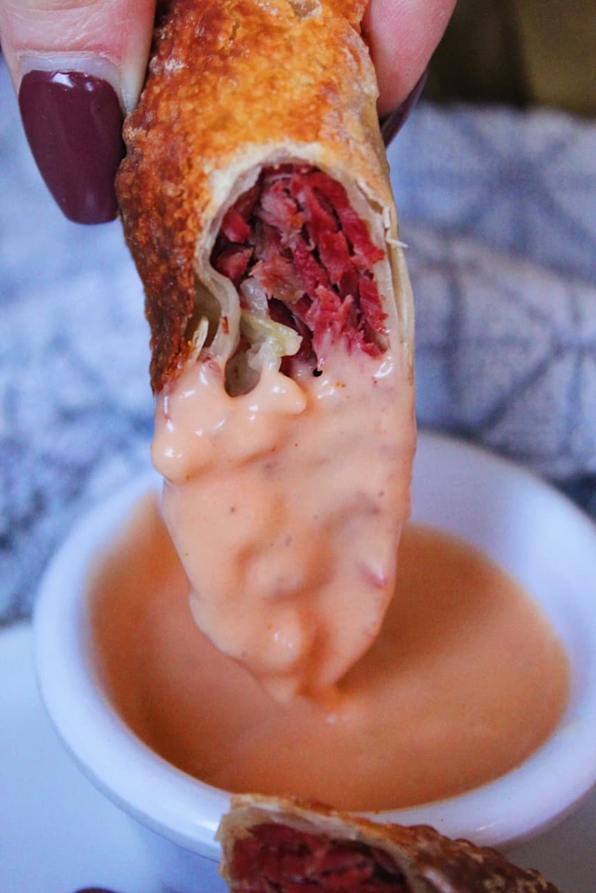 Reuben Egg Roll sliced in half and dipped in Thousand Island Dressing.