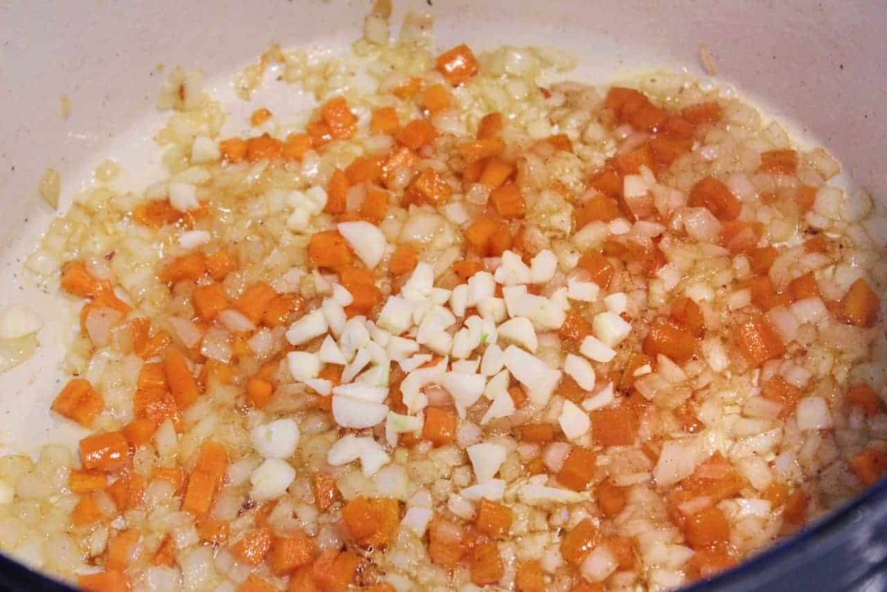 Onion, carrot, and garlic sauteing in a large dutch oven.