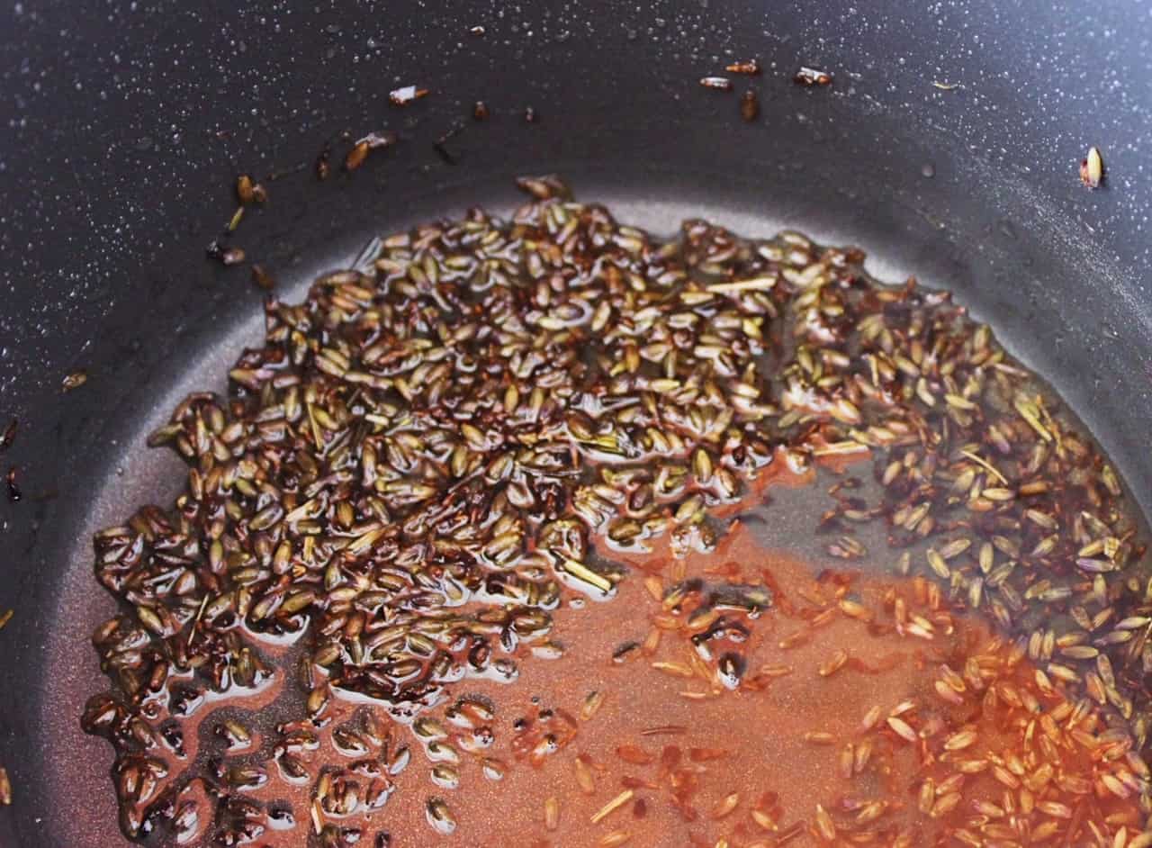 Dried lavender, sugar and water simmering in a black pot.
