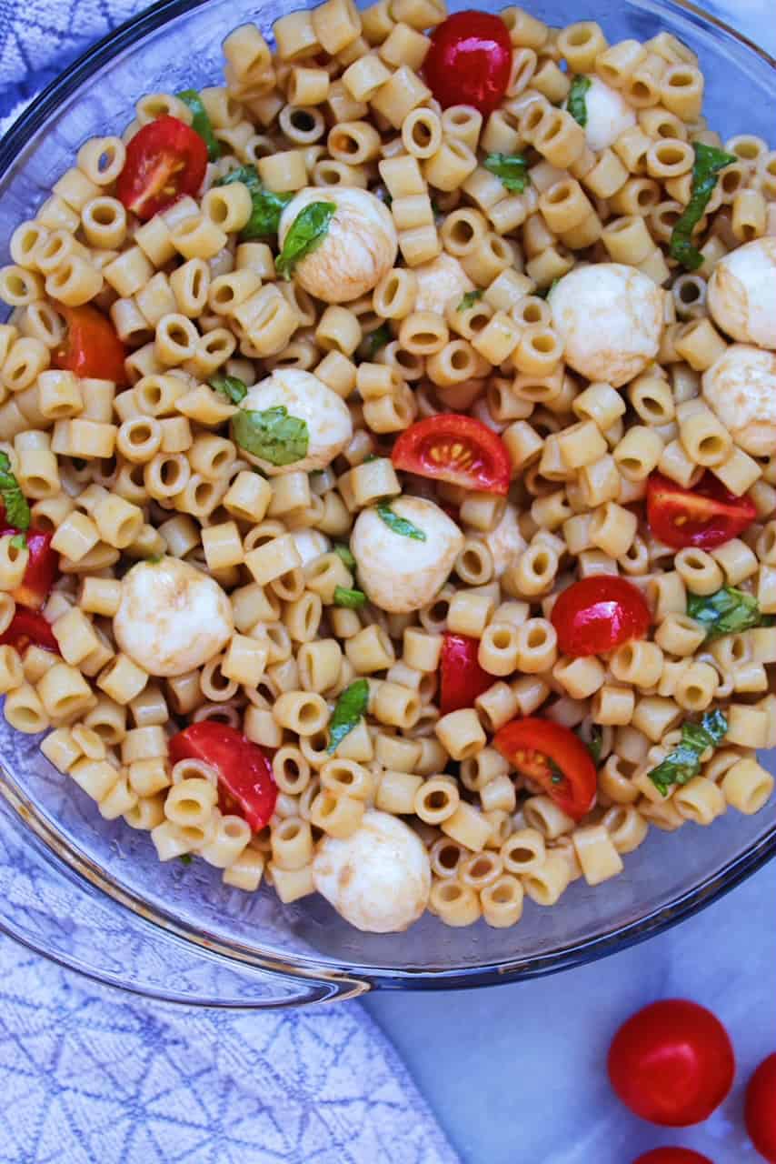 Tomato Mozzarella Pasta Salad in a bowl next to grey towel.
