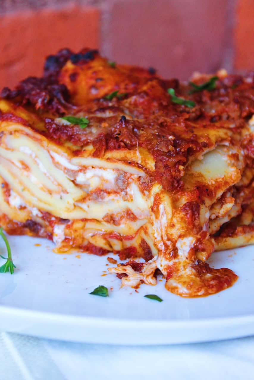 Cheesy layers of lasagna served on a white plate.