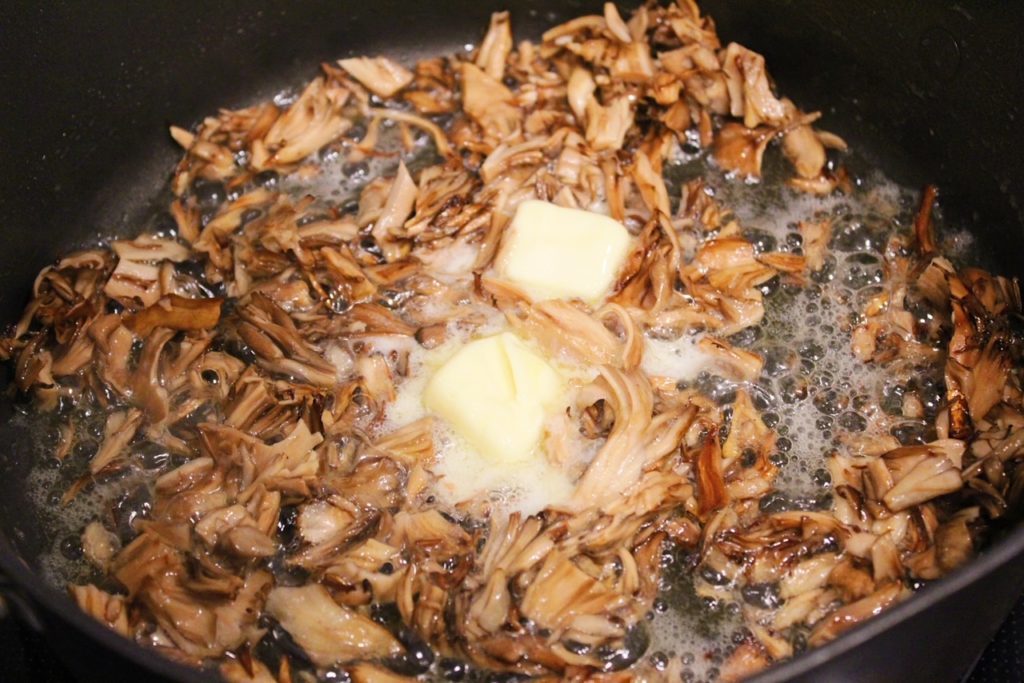 adding butter to mushrooms