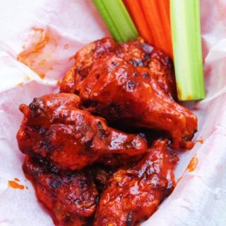 Crispy Air Fryer Hot Wings in a parchment paper lined basket with celery and carrots.
