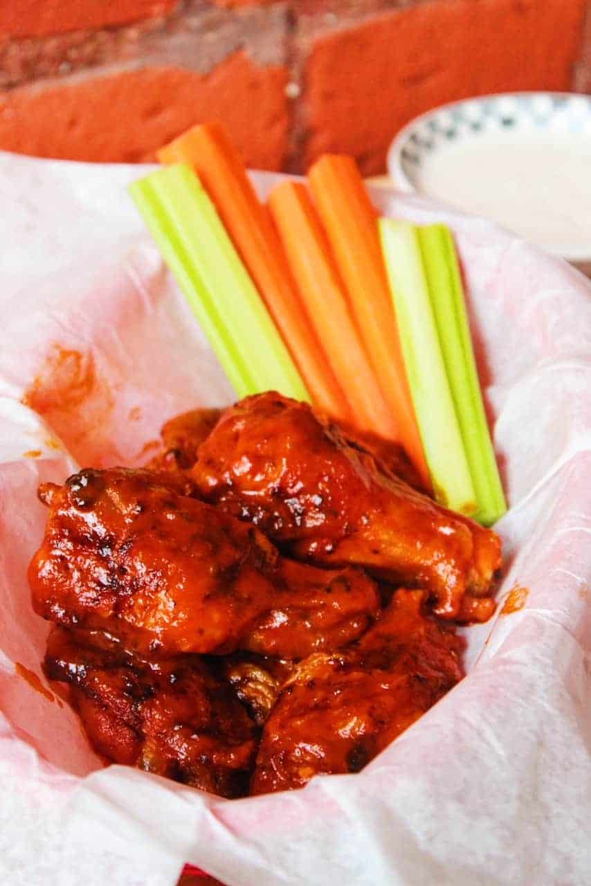 Crispy Air Fryer Hot Wings in a parchment paper lined basket with celery and carrots.