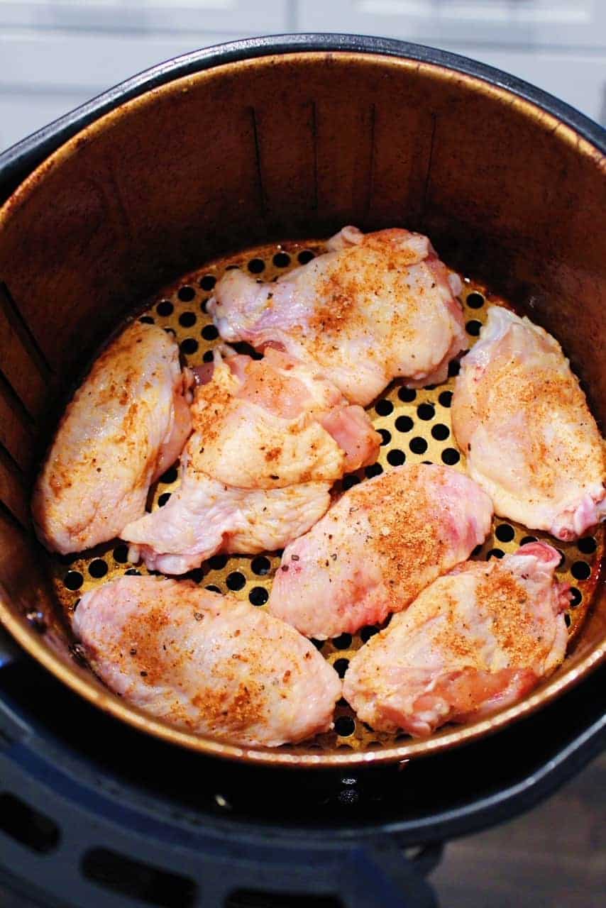 Dry rubbed chicken wings in the basket of an airy fryer.