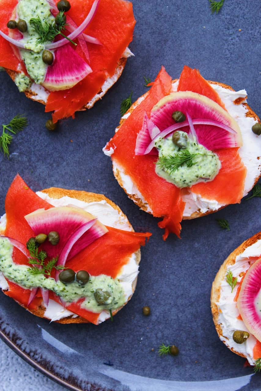 Close up image of bagels stacked with toppings on grey plate.