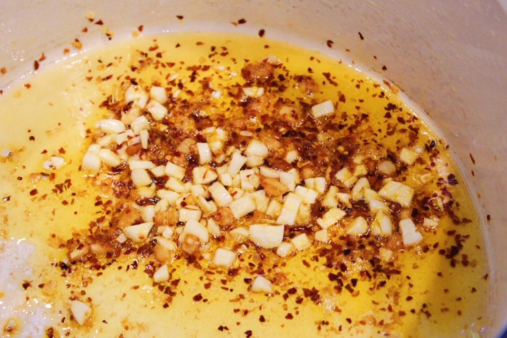 Sauteing garlic and red pepper flakes in olive oil in large dutch oven.