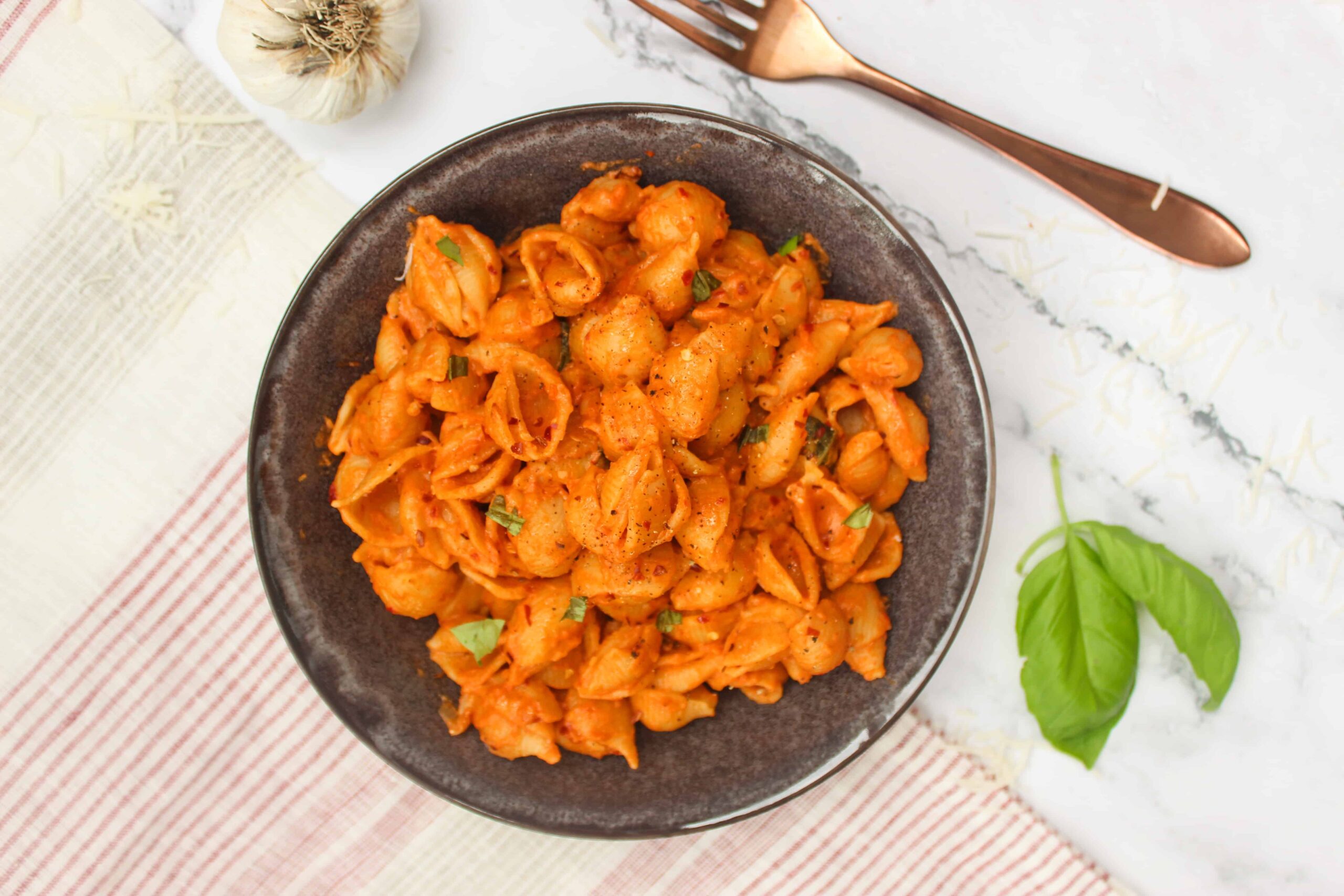 Gigi Hadid Pasta in a bowl with fresh basil and garlic.