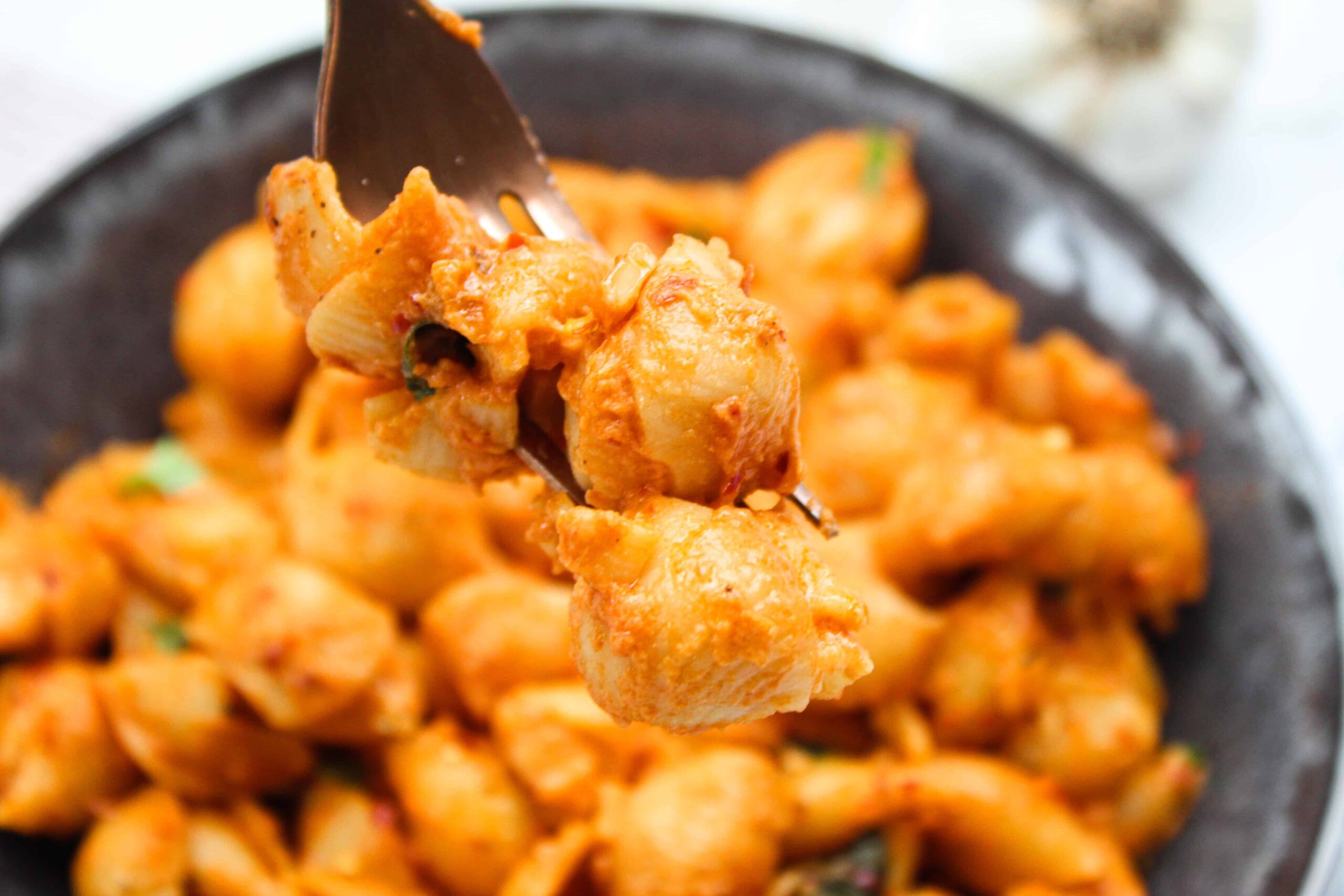 A fork holding Gigi Hadid Pasta with Spicy Vodka sauce shells over a bowl.