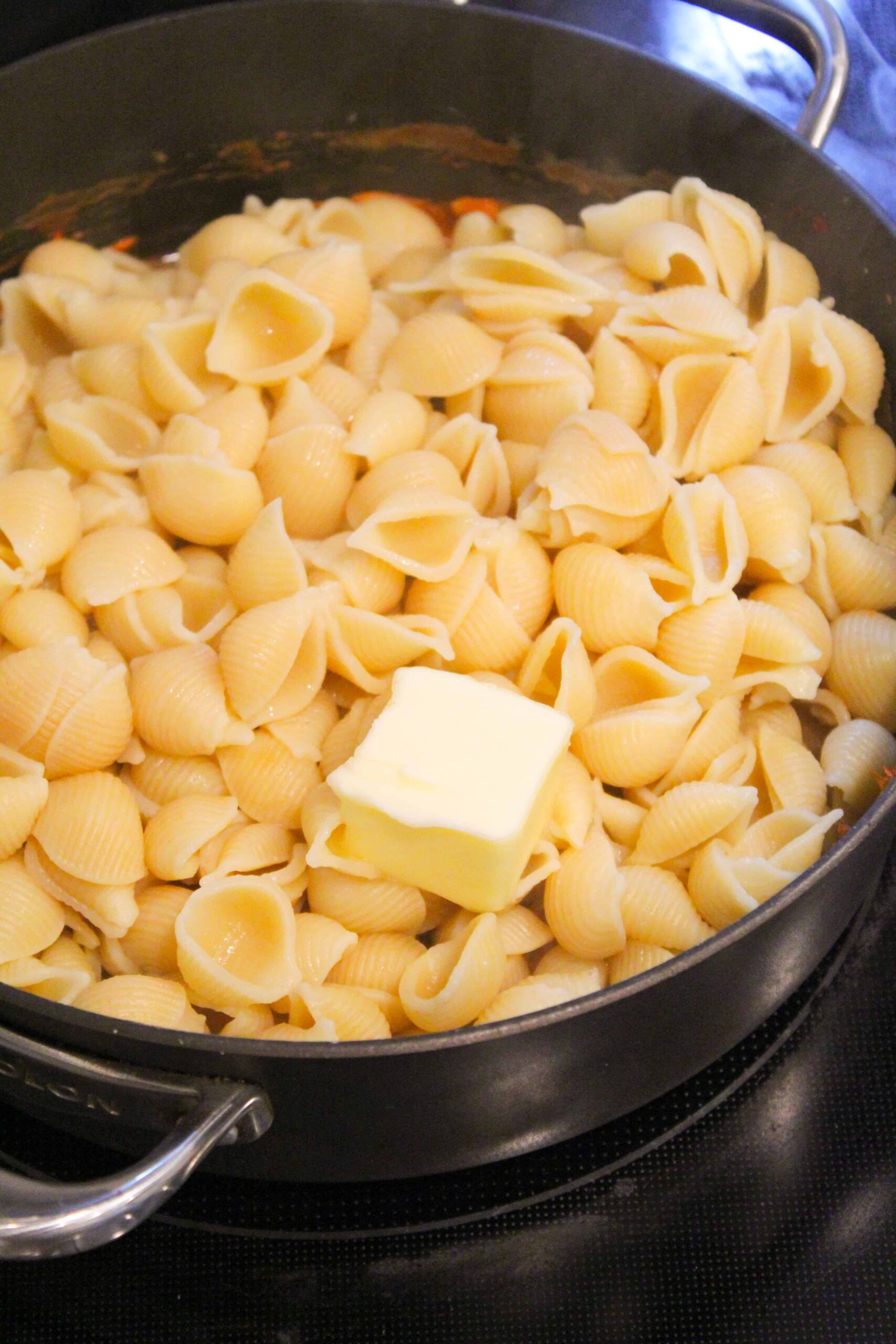 Butter being added to cooked shell pasta.