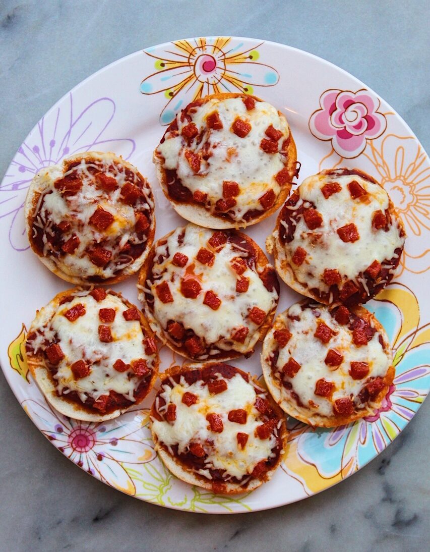 Homemade pizza bagels fresh out of the oven sitting on a floral plate.
