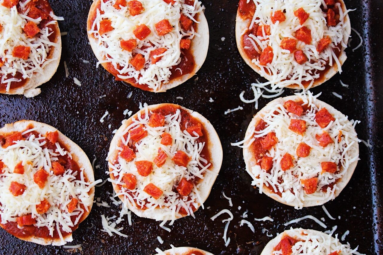 Close up of mini bagels stacked with marinara, mozzarella and pepperoni.