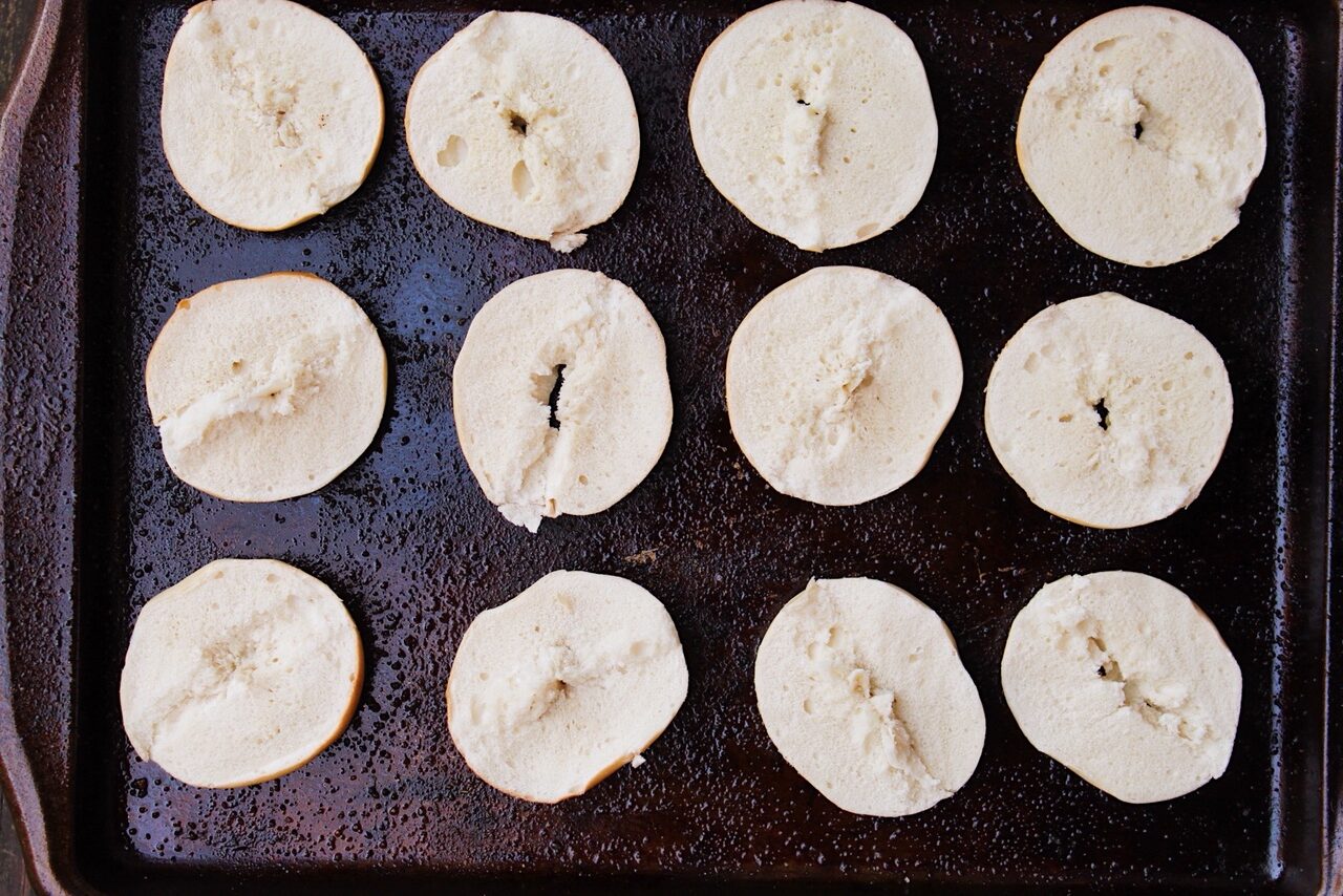 Mini bagels, halved, on a baking sheet.