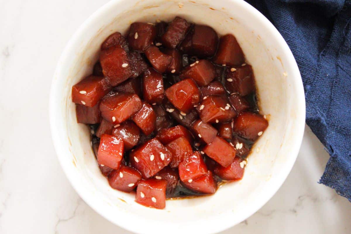 Tuna poke marinating in a small white bowl.