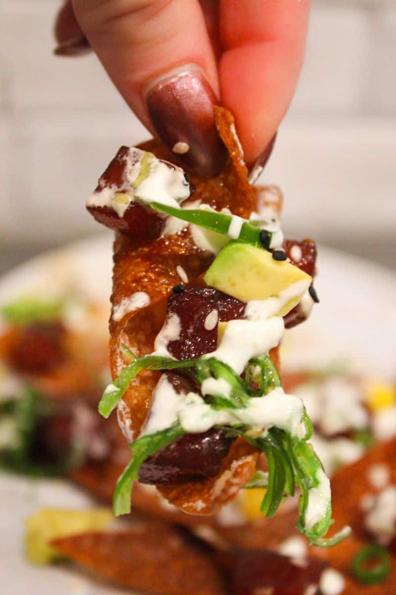 Close up picture of tuna, avocado, jalapeno, and seaweed salad on a wonton chip. 