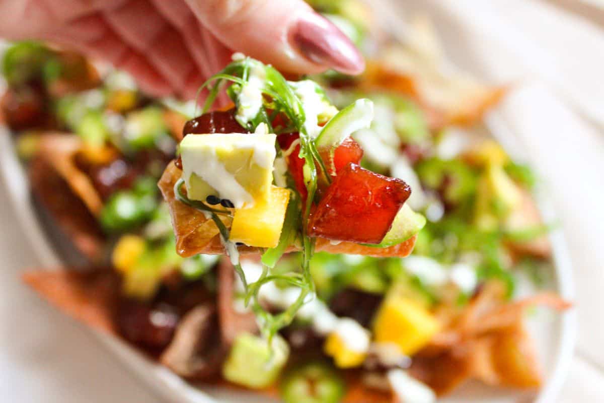 Up close picture of tuna, avocado and mango on a wonton nacho.