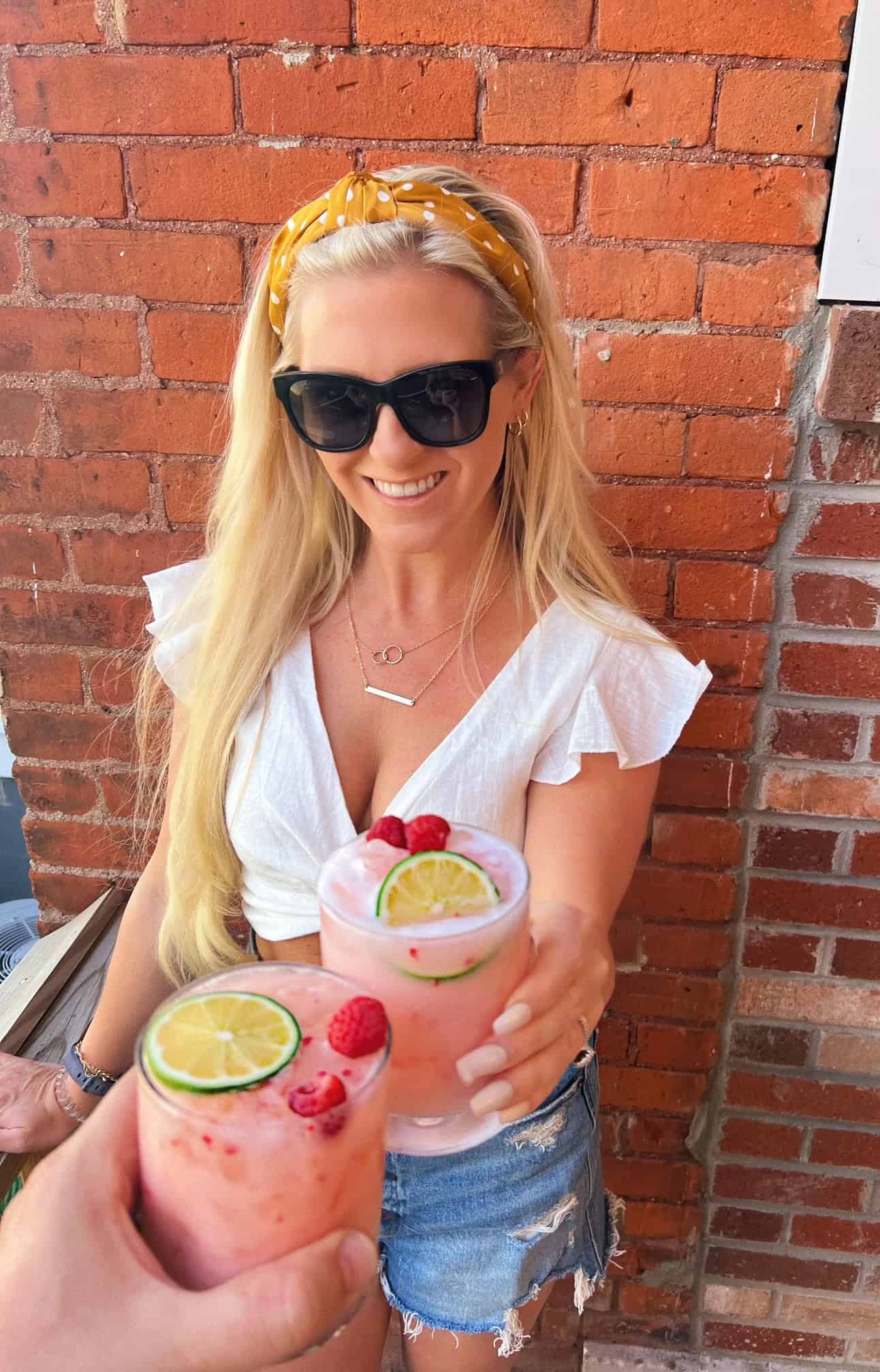 Laura holding a coconut margarita cheersing with another.