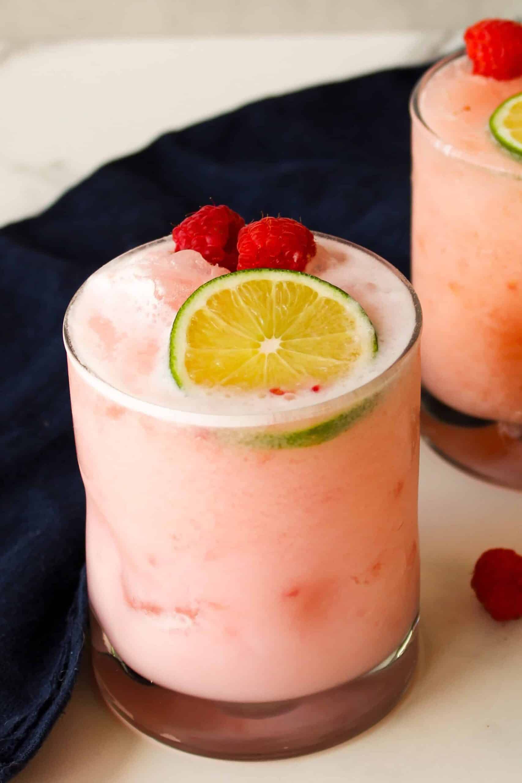 Close up shot of light pink raspberry coconut margarita in a rocks glass.