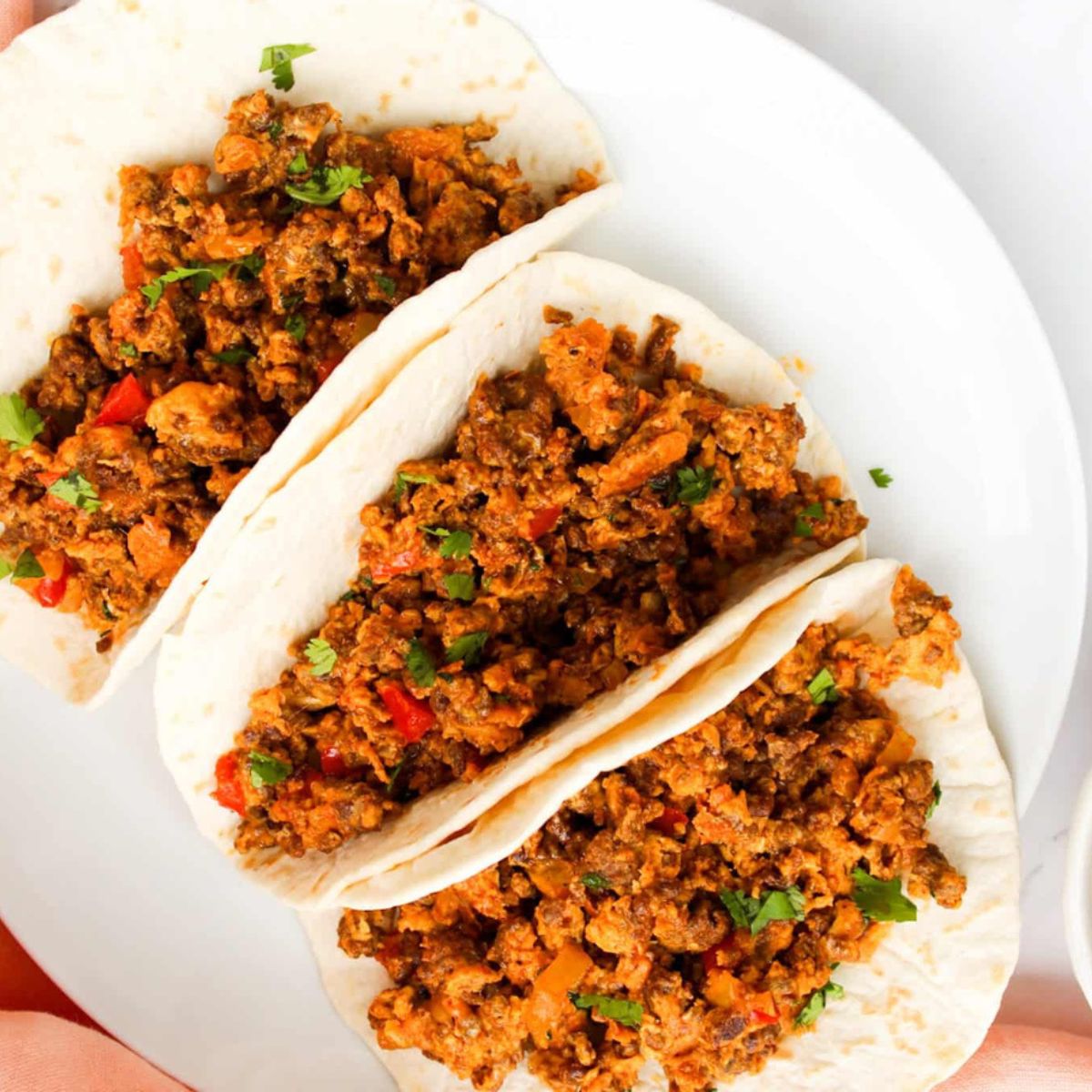 Overhead image of Chorizo Breakfast tacos in tortillas on a white plate.